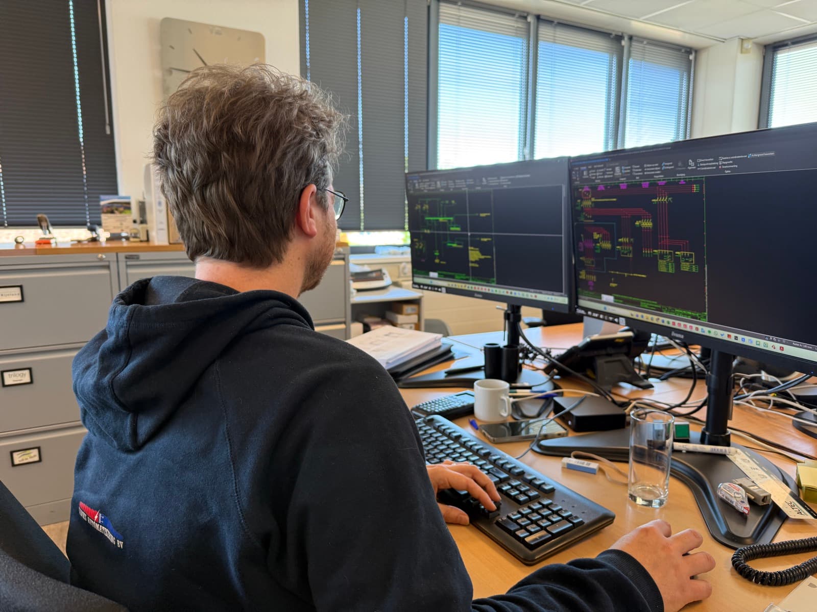 Medewerker van Kadiks Automatisering BV aan het werk achter meerdere beeldschermen